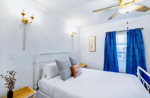 1 dormitorio con cama blanca y cortinas azules en Old Spanish House- C, The Madeleine Suite, en Biloxi