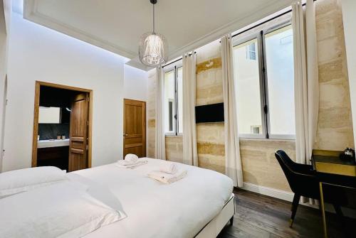 1 dormitorio con 1 cama, escritorio y ventanas en Château Trompette Tourny, en Burdeos