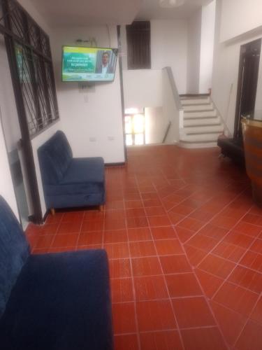 Sala de espera con silla azul y TV en Hotel Olympo en Ibagué