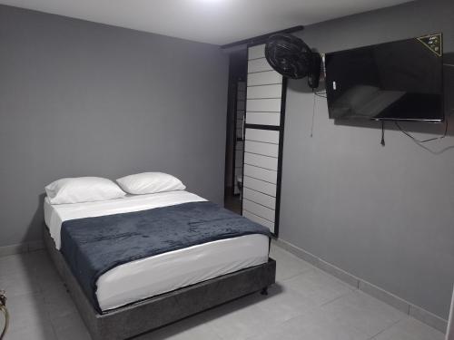 a bedroom with a bed and a flat screen tv at Hotel Olympo in Ibagué