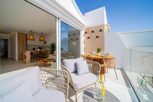 a balcony with white chairs and a table and a kitchen at Casa Boga in Puerto del Carmen
