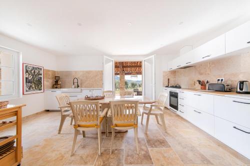 une cuisine avec des armoires blanches et une table et des chaises en bois dans l'établissement La Maison de Jean - Charmante maison avec stock tank, à La Bouilladisse