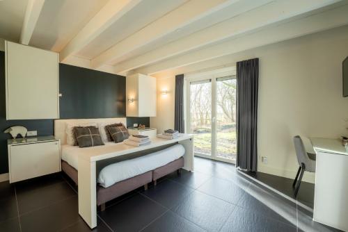 a bedroom with a bed with a desk and a window at De Rietreiger in Blankenberge