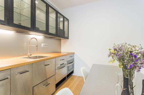 una cocina con fregadero y una mesa con un jarrón de flores en My Space Barcelona - 2 Bedroom Apartment in uptown, en Barcelona