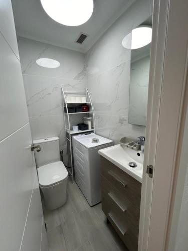a white bathroom with a toilet and a sink at Skyline 21 in Torrevieja