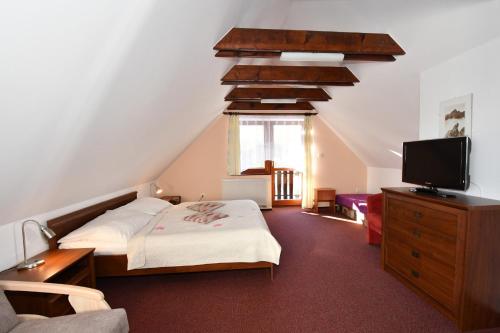 a bedroom with two beds and a flat screen tv at Penzion Lesna in Vysoké Tatry