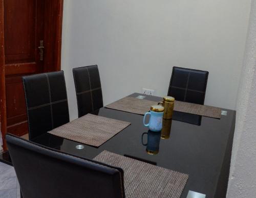 Una mesa negra con sillas y una botella. en Peace cottage short lets and apartments, en Ibadán