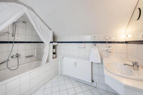 a white bathroom with a tub and a sink at Hotel Birke - Appartments Waldesruh in Kiel