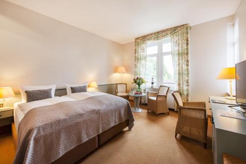 a bedroom with a bed and a desk and a window at Hotel Birke - Appartments Waldesruh in Kiel