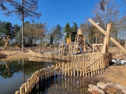 een speeltuin met een houten hek rond een vijver bij Camping Het Horstmannsbos in Gasselte