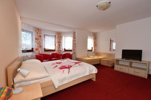 a bedroom with a bed with red chairs and a television at Penzion Lesna in Vysoke Tatry - Tatranska Lesna