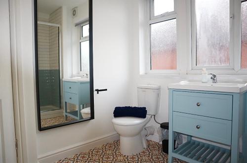 een badkamer met een toilet, een wastafel en een spiegel bij Large Capacity Comfortable Group Stay in Nottingham