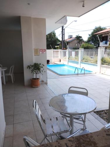 un patio con mesa y sillas junto a una piscina en Apartamento de 2 quartos a 3 minutos a pé da praia de Cachoeira de Bom Jesu com águas calmas, en Florianópolis