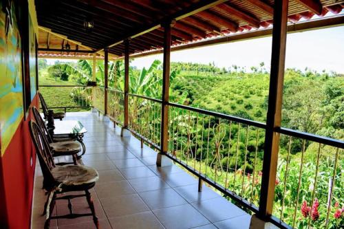 een balkon met stoelen en uitzicht op een veld bij hotel villa nazareth in Quimbaya