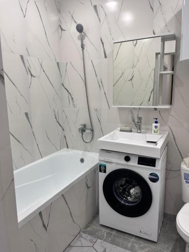 ein Badezimmer mit einer Waschmaschine und einem Waschbecken in der Unterkunft Уютная однокомнатная квартира в центре города in Kökschetau