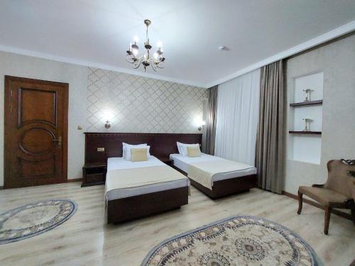 a hotel room with two beds and a chandelier at Hotel Times in Bukhara
