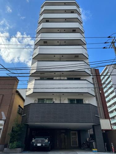 a tall building with a car parked in front of it at CAlMU ASAKUSA HOTEL ASAKUSA UENO IMADOZINZYA TOKYOSKYTREE HANEDA NARITA GINZA TOKYOSTATION Direct 浅草上野東京スカイツリー 成田空港羽田空港東京駅直行バス 電車便利 in Tokyo