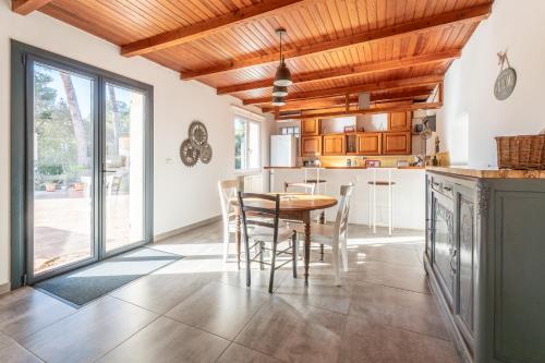 cocina con techos de madera, mesa y sillas en Maison provençale, en Cornillon-Confoux