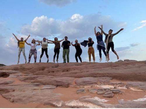 a group of people jumping on top of some rocks at Night Magic Camp in Wadi Rum
