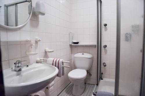 a white bathroom with a toilet and a sink at Weigands Hotel Peter in Reinhardshagen