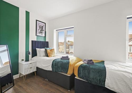 two beds in a room with green and white walls at 124 Vere Road in Peterborough