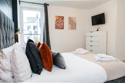 a bedroom with a white bed with pillows and a window at Comfy & spacious Apt, 2 balconies, near the 02 arena, Greenwich in London