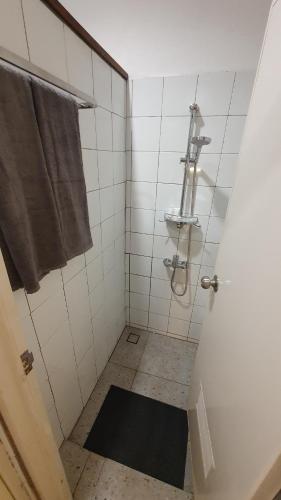 a white bathroom with a shower with a towel at Kartika Lodge in Bengkok