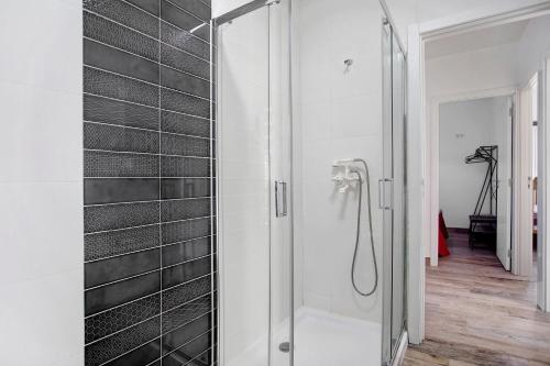 y baño con ducha y azulejos negros. en Casa da Padaria, en Leiria