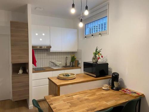 une cuisine avec une table en bois et un micro-ondes dans l'établissement Nid douillet tout équipé, à Château-Renault