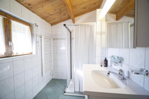 a white bathroom with a sink and a shower at Chasa Avant Porta in Ramosch