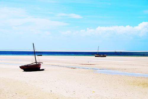 two boats are sitting on the sand on a beach at Vilancool Beach Resort in Vilanculos