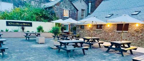 a group of picnic tables with umbrellas in front of a building at The Kings Head Hotel in Abergavenny