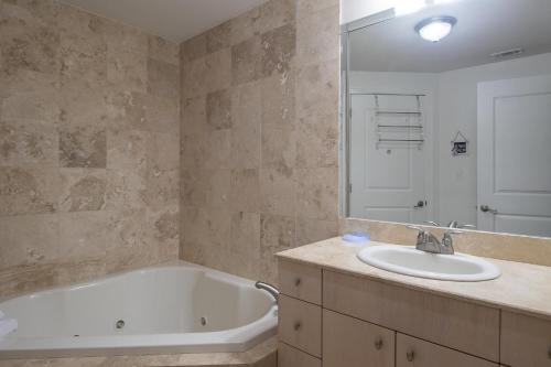 een badkamer met een bad, een wastafel en een spiegel bij Sea Breeze 908 in Biloxi