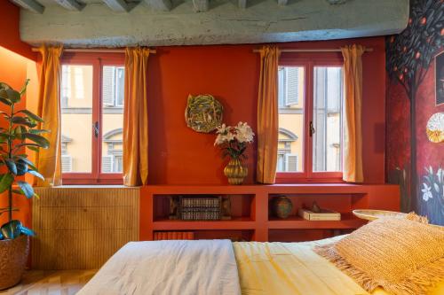 Schlafzimmer mit orangefarbenen Wänden und Fenstern sowie einem Bett in der Unterkunft Casa Lilia - Florence in Florenz