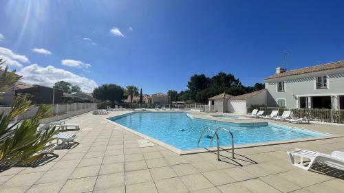 une grande piscine avec des chaises et une maison dans l'établissement Villa Aquatica Piscine & Plage, à Plage-des-Demoiselles
