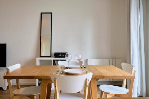 une salle à manger avec une table en bois et des chaises blanches dans l'établissement Apartment balconyparking space near train station, à Lille