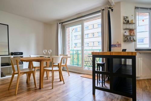 une salle à manger avec une table et des chaises et une grande fenêtre dans l'établissement Apartment balconyparking space near train station, à Lille