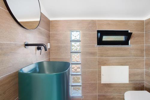 La salle de bains est pourvue d'un lavabo vert et d'un miroir. dans l'établissement Casa Do Lenhador, à Canhas