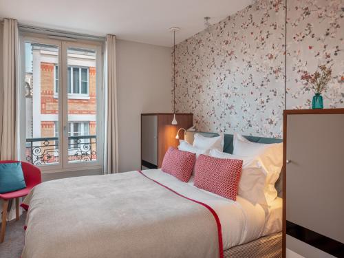 a bedroom with a large bed with pink pillows at Hotel Le Mareuil in Paris