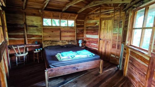 Bett in einem Blockhaus mit einem Tisch in der Unterkunft Jungle Cabins El Escondido in Muy Muy