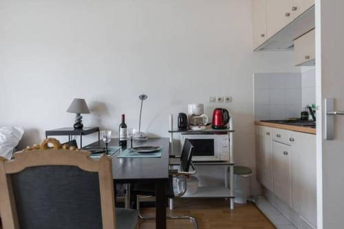 Il comprend une cuisine équipée d'une table à manger et d'un four micro-ondes. dans l'établissement Le Cozy Appartement + balcon ensoleillé + Parking, à Paris