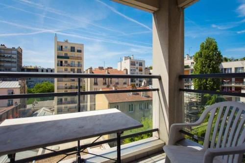 un balcon avec un banc et une vue sur une ville dans l'établissement Le Cozy Appartement + balcon ensoleillé + Parking, à Paris