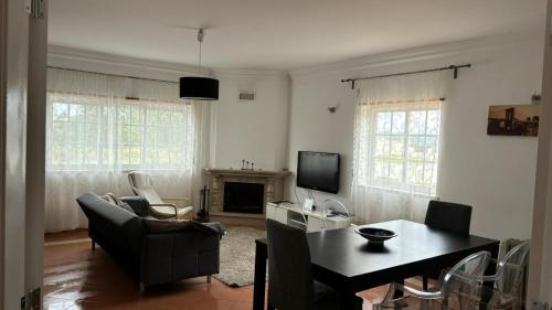 een woonkamer met een tafel en stoelen en een televisie bij Windmill Ericeira in Ericeira