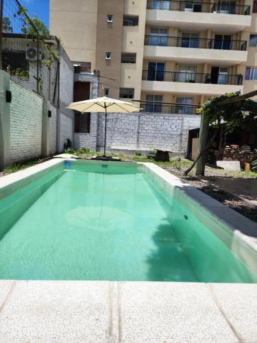 a swimming pool with an umbrella next to a building at Salta eco alojamiento in Salta