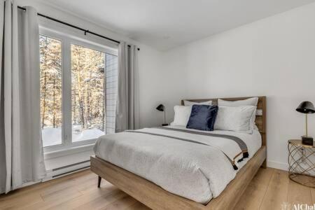 a bedroom with a large bed and a large window at Dahlia 2 avec piscine in Valcartier Station