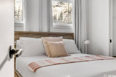 a bedroom with a bed with white pillows and a window at BLOOM - Luxe et Confort en forêt in Valcartier Station