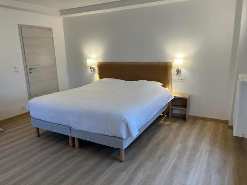 um quarto com uma grande cama branca e piso em madeira em Résidence de la Roseraie em Florenville