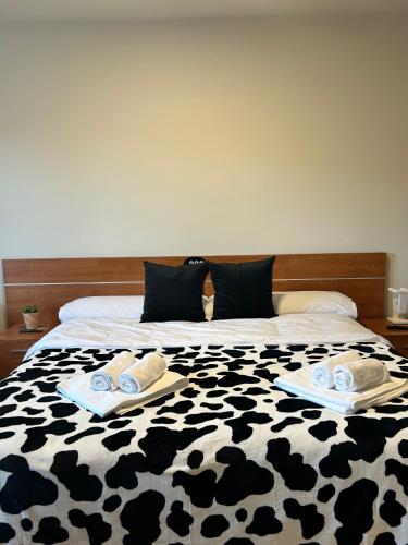 a black and white bed with towels on it at Bicis & Vacas in La Pola de Gordón