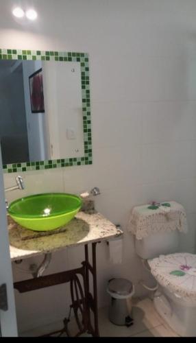 La salle de bains est pourvue d'un lavabo vert et de toilettes. dans l'établissement Apartamento disponível 1 dormitório, à Tramandaí