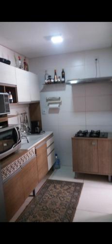 - une cuisine avec des murs blancs et des placards en bois dans l'établissement Apartamento disponível 1 dormitório, à Tramandaí